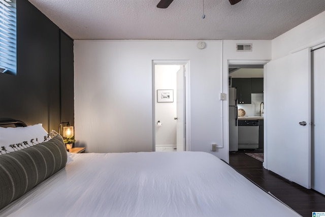 bedroom with ceiling fan, stainless steel refrigerator, dark hardwood / wood-style floors, and a textured ceiling