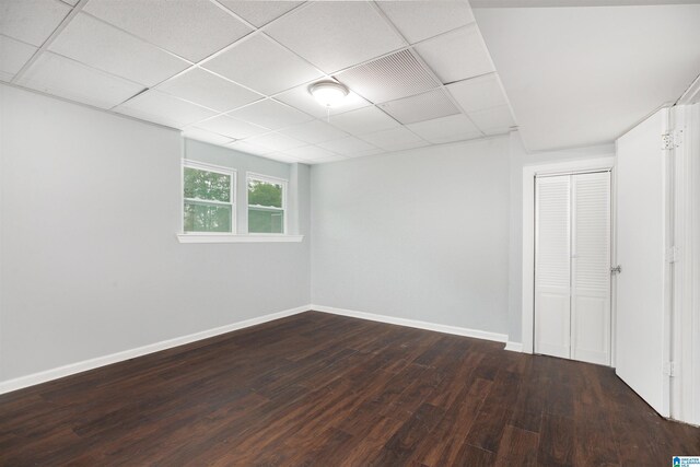 interior space with a paneled ceiling, dark wood-type flooring, and a closet