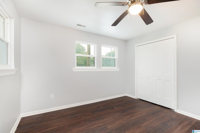 unfurnished bedroom featuring dark hardwood / wood-style floors, ceiling fan, and a closet