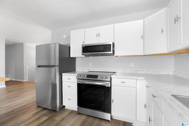 kitchen with light stone counters, appliances with stainless steel finishes, dark hardwood / wood-style floors, and white cabinetry