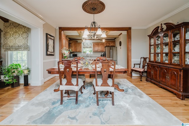 dining space with light wood-type flooring, ornamental molding, sink, and a chandelier