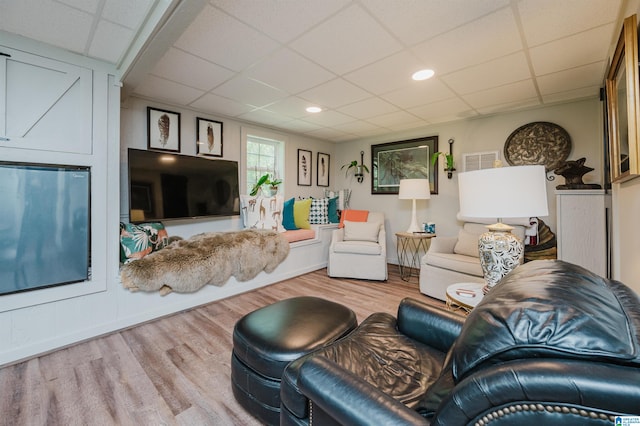 living room with light wood-type flooring and a paneled ceiling