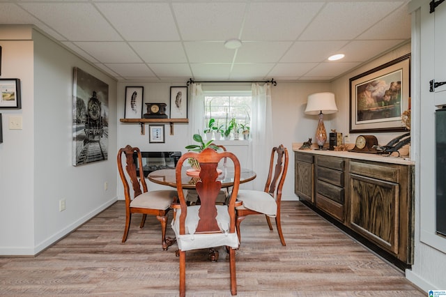 dining space with a drop ceiling and light hardwood / wood-style floors