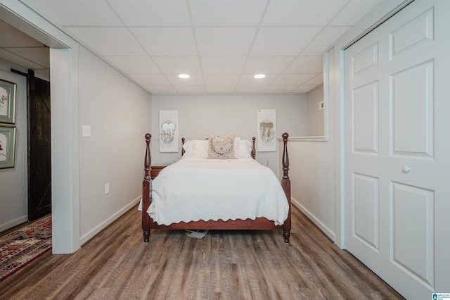 bedroom with a paneled ceiling and hardwood / wood-style floors