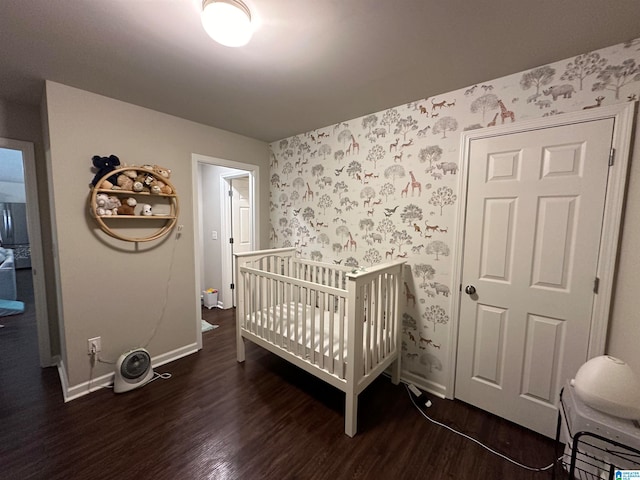 bedroom featuring a crib and dark wood-type flooring