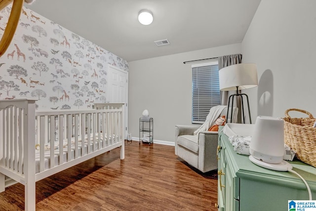 bedroom featuring a crib and dark hardwood / wood-style floors