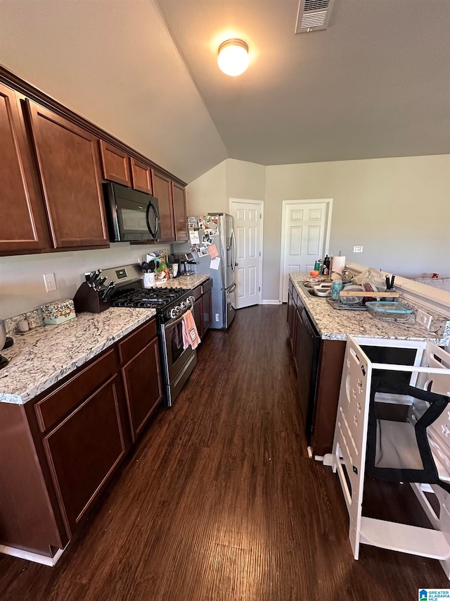 kitchen featuring light stone countertops, appliances with stainless steel finishes, dark hardwood / wood-style flooring, and lofted ceiling