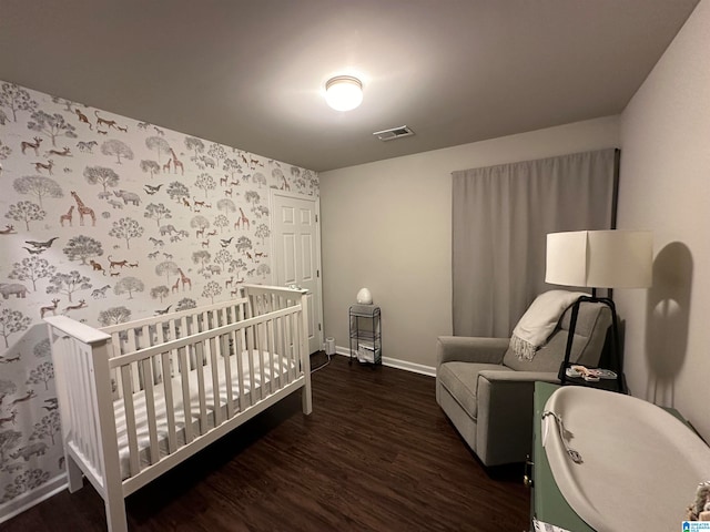 bedroom with a crib and dark hardwood / wood-style floors