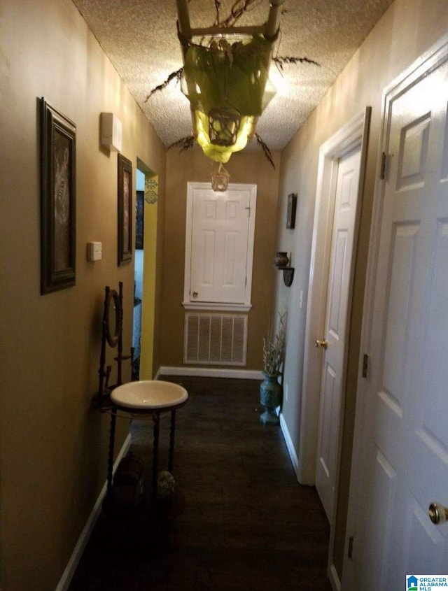 hallway with a textured ceiling and dark wood-type flooring