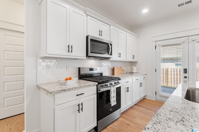 kitchen featuring white cabinets, appliances with stainless steel finishes, and light hardwood / wood-style floors