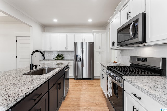 kitchen with white cabinets, light stone countertops, stainless steel appliances, light hardwood / wood-style flooring, and sink