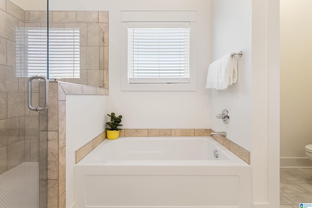 bathroom featuring tile patterned floors, toilet, plus walk in shower, and a wealth of natural light