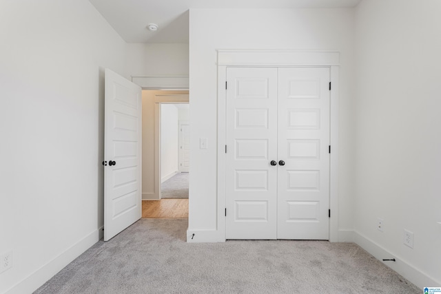 unfurnished bedroom with a closet and light colored carpet