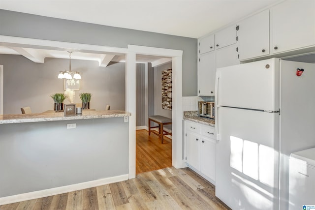 kitchen with pendant lighting, white refrigerator, white cabinets, beam ceiling, and light hardwood / wood-style flooring