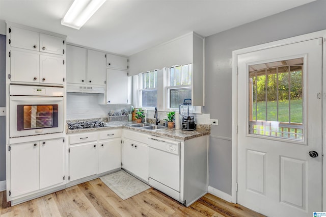 kitchen with light wood-type flooring, sink, white appliances, and white cabinetry