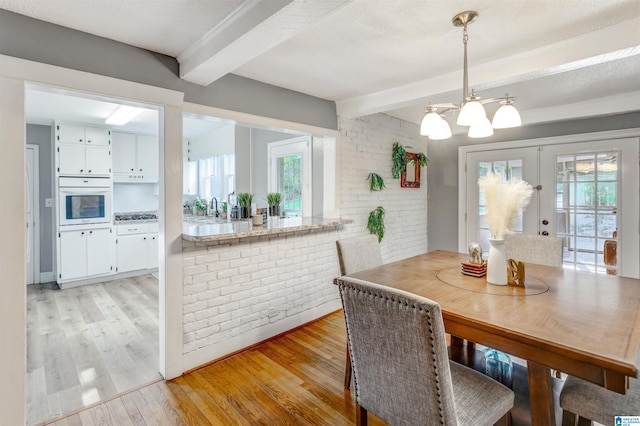 dining space with light hardwood / wood-style flooring, brick wall, and plenty of natural light