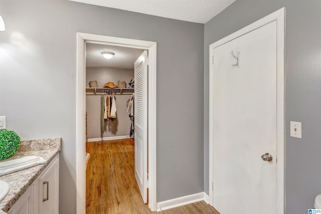 interior space with a textured ceiling, wood-type flooring, and vanity