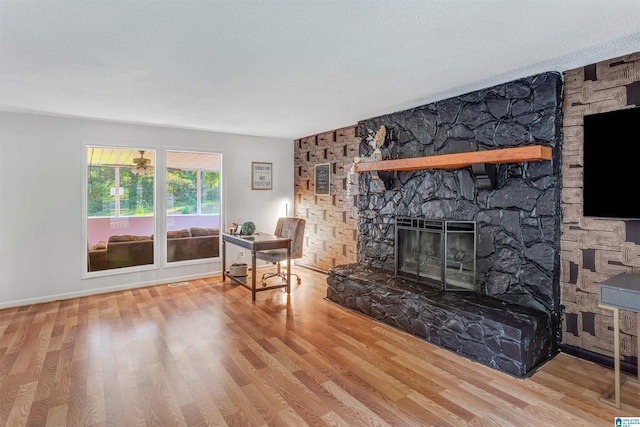 living room with wood-type flooring and a stone fireplace