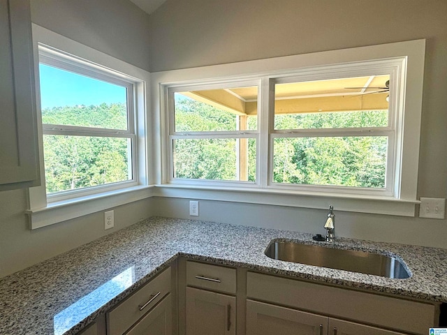 kitchen featuring light stone counters and sink