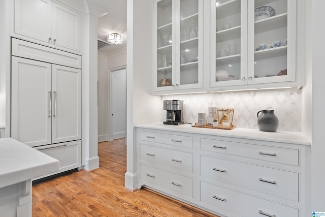 interior space featuring decorative backsplash, ornamental molding, light hardwood / wood-style flooring, and white cabinetry