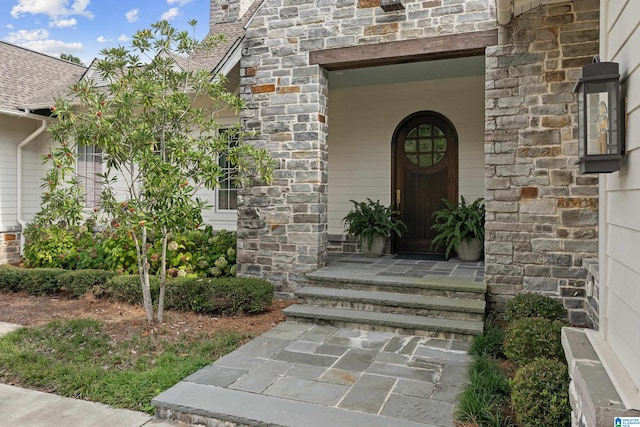 doorway to property featuring stone siding and a chimney