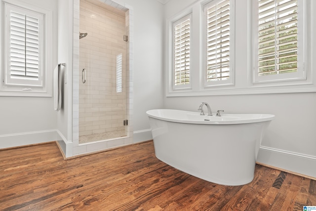 bathroom with wood-type flooring and shower with separate bathtub