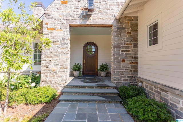 doorway to property with stone siding and covered porch