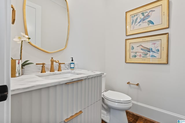 bathroom with vanity, toilet, and hardwood / wood-style flooring