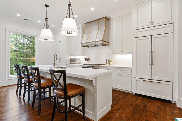 kitchen with a center island with sink, custom range hood, dark hardwood / wood-style flooring, and white cabinetry