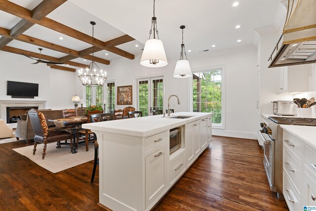 kitchen featuring a center island with sink, dark hardwood / wood-style flooring, pendant lighting, and white cabinets