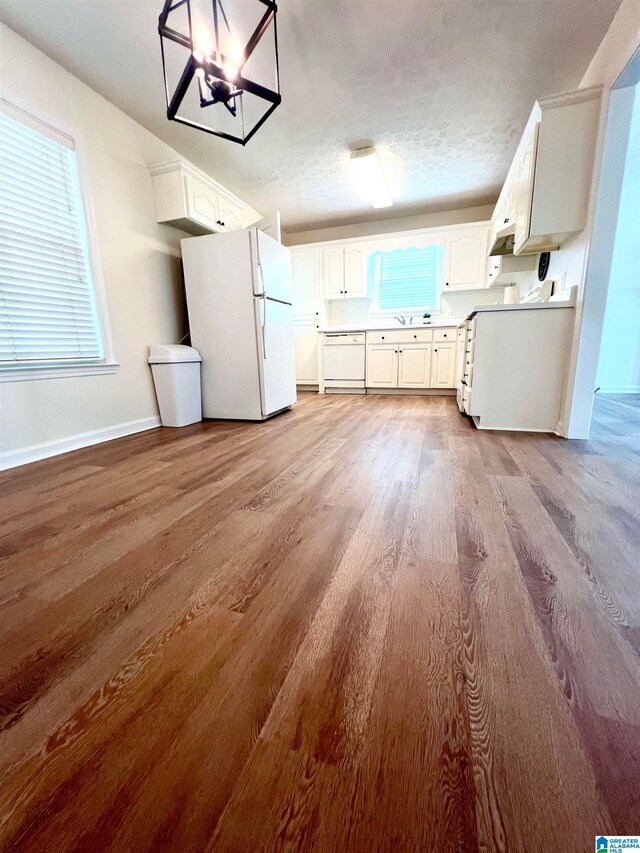 kitchen featuring light hardwood / wood-style floors, white cabinets, white appliances, decorative light fixtures, and a notable chandelier