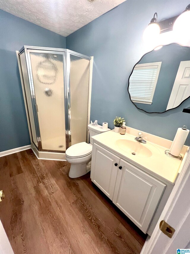 bathroom featuring toilet, vanity, hardwood / wood-style floors, and a shower with shower door