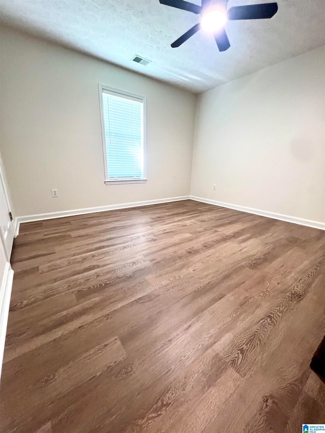 empty room featuring ceiling fan, dark hardwood / wood-style floors, and a textured ceiling