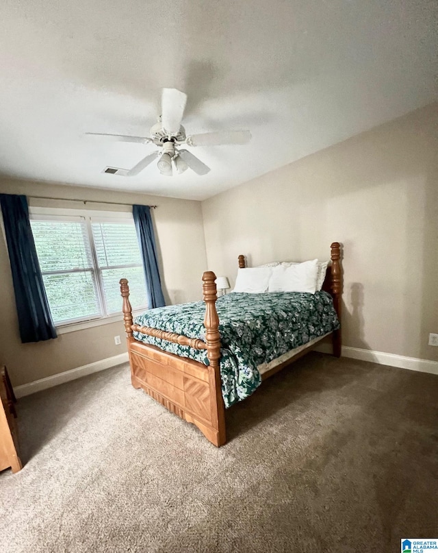 bedroom with ceiling fan, a textured ceiling, and dark colored carpet