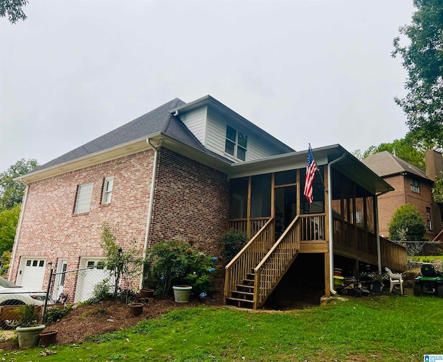 rear view of property with a sunroom, a lawn, and a garage