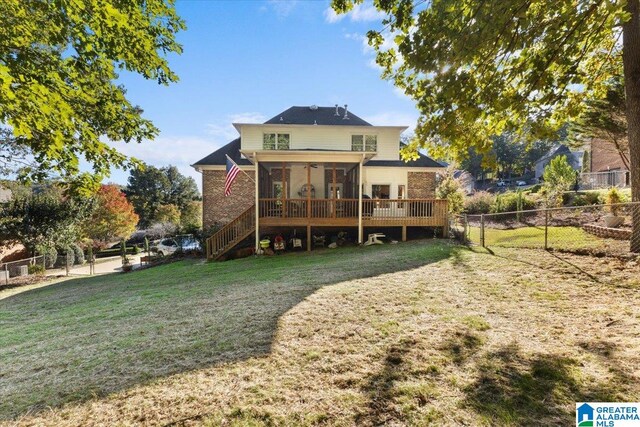 rear view of house with a deck, a sunroom, and a lawn