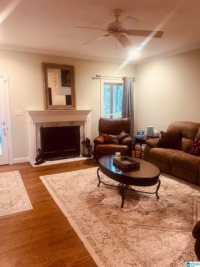 living room with ornamental molding, a fireplace, hardwood / wood-style flooring, and ceiling fan