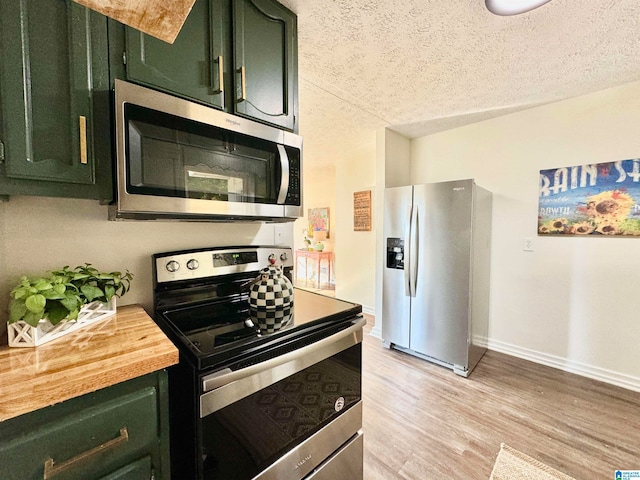 kitchen with a textured ceiling, green cabinets, stainless steel appliances, and light hardwood / wood-style flooring