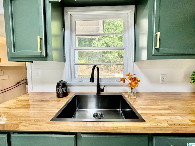 kitchen featuring butcher block countertops, green cabinetry, and sink