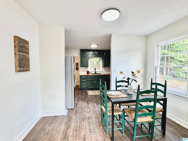 dining space featuring a textured ceiling, sink, and hardwood / wood-style floors