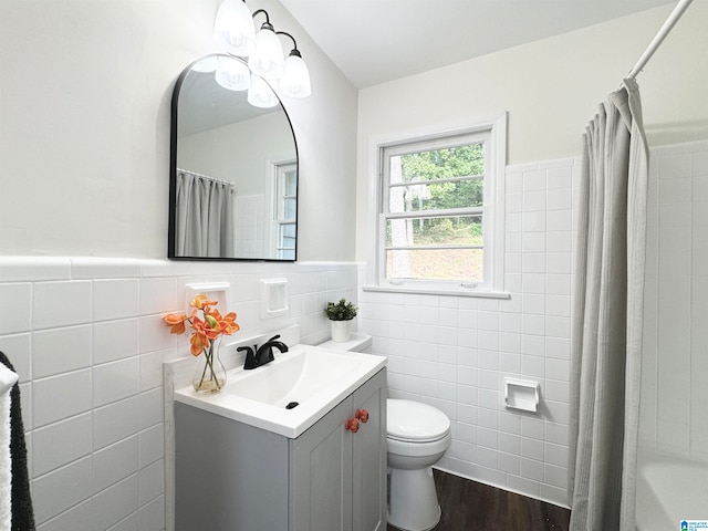 bathroom featuring wood-type flooring, vanity, tile walls, and toilet