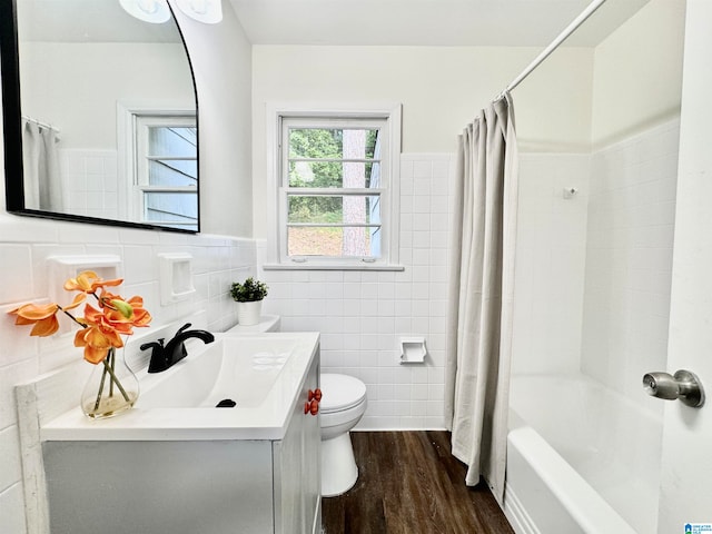 full bathroom featuring tile walls, hardwood / wood-style flooring, shower / bathtub combination with curtain, vanity, and toilet