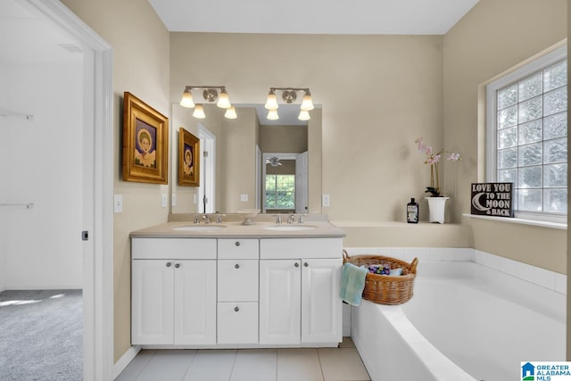 bathroom with tile patterned floors, a washtub, and vanity