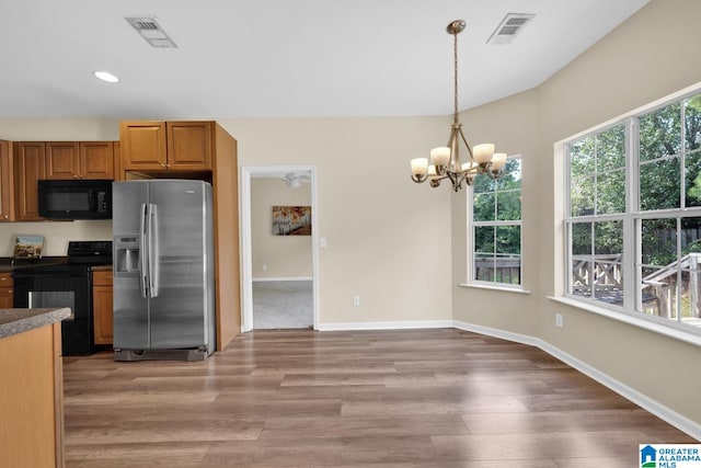 kitchen with wood-type flooring, an inviting chandelier, decorative light fixtures, and black appliances