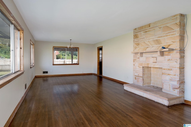 unfurnished living room with dark hardwood / wood-style flooring and a stone fireplace