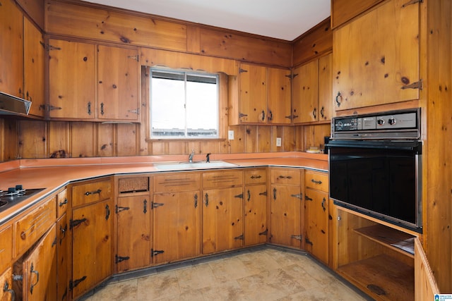 kitchen featuring oven, wood walls, and sink