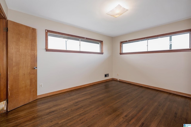 spare room with dark hardwood / wood-style flooring and a wealth of natural light