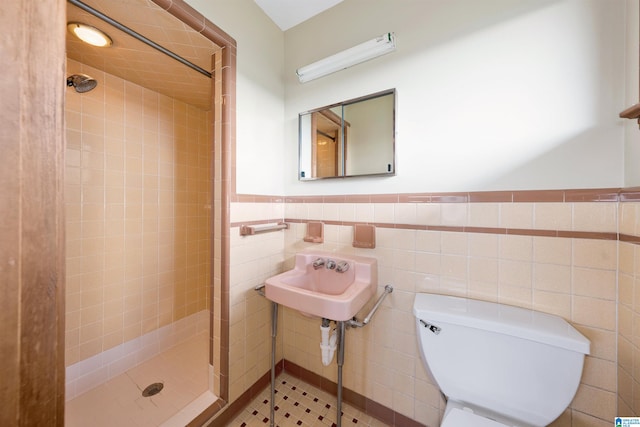 bathroom with tile walls, tile patterned flooring, sink, tiled shower, and toilet