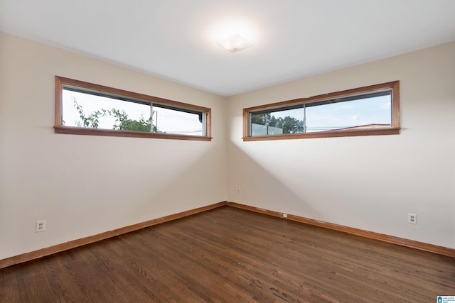 empty room with a healthy amount of sunlight and dark hardwood / wood-style flooring