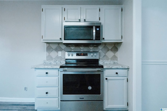 kitchen with white cabinets, stainless steel appliances, light stone countertops, and tasteful backsplash